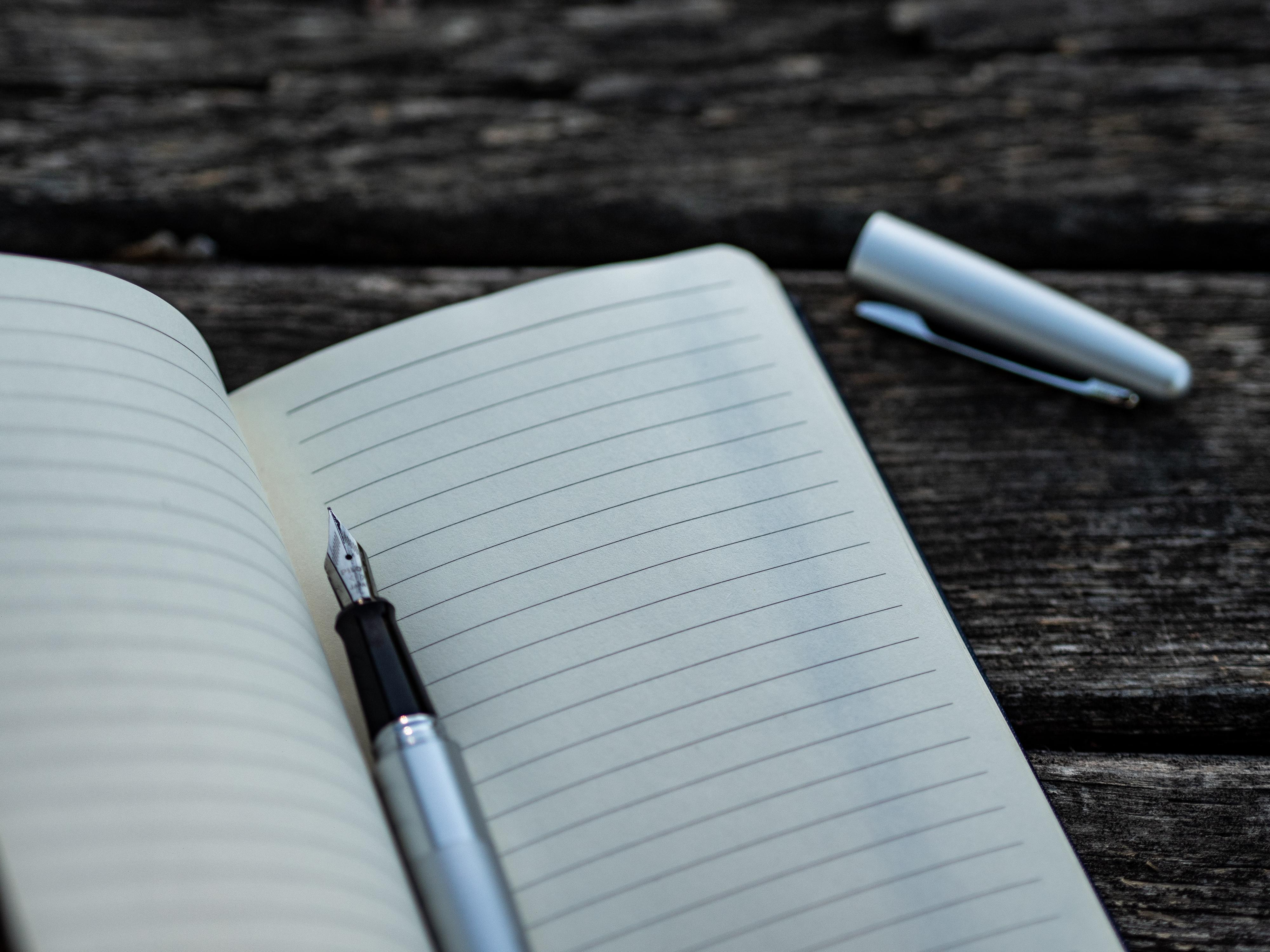 Aufgeschlagenes Notizbuch auf einem Tisch mit Stift