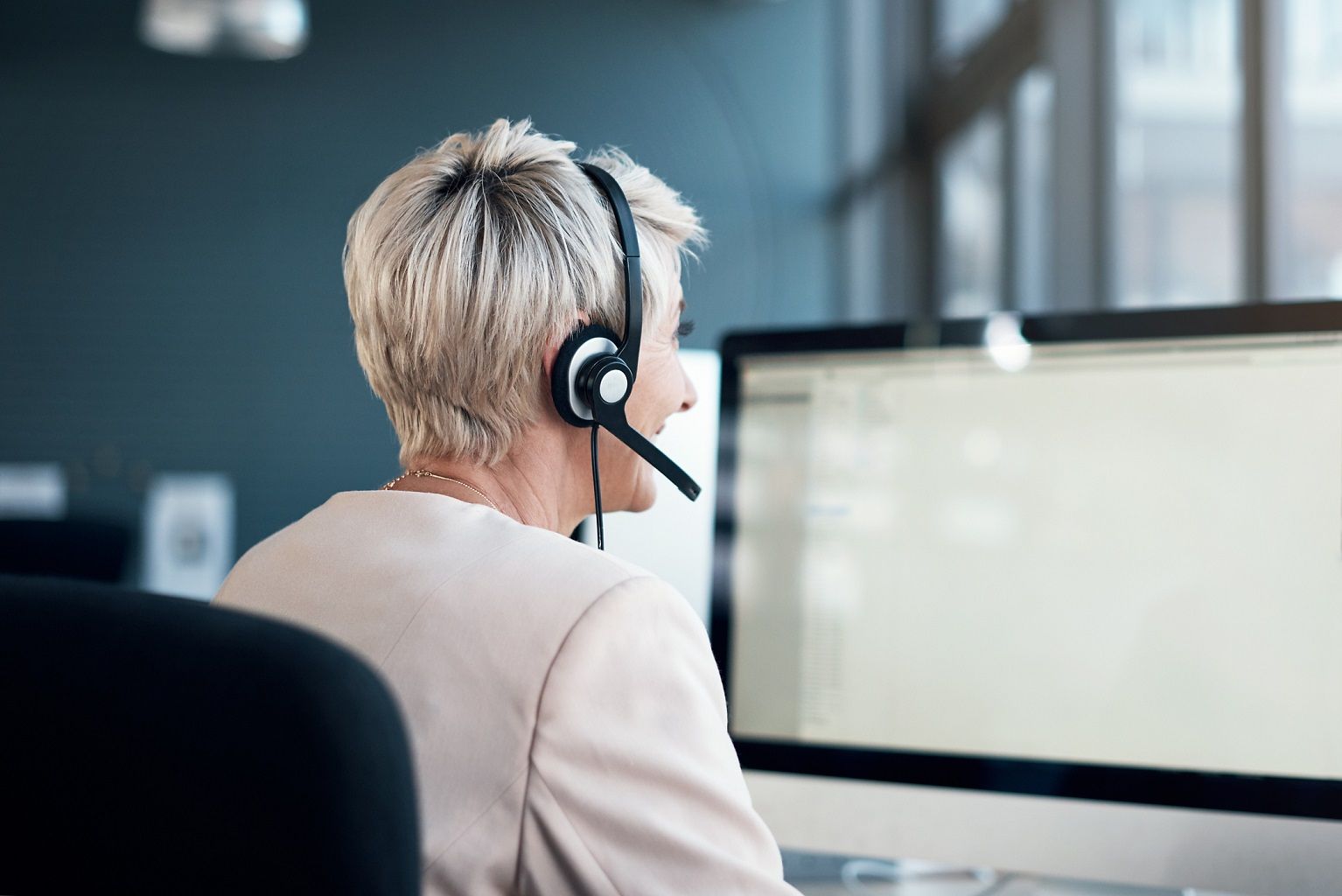 Frau mit Headset am Computer/Bildschirm