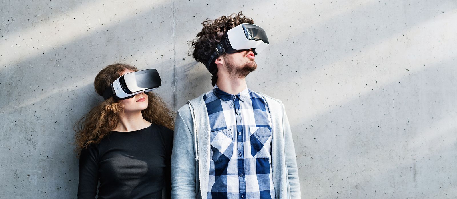 Junge Frau und junger Mann stehen vor einer Wand. Beide haben VR-Brillen auf