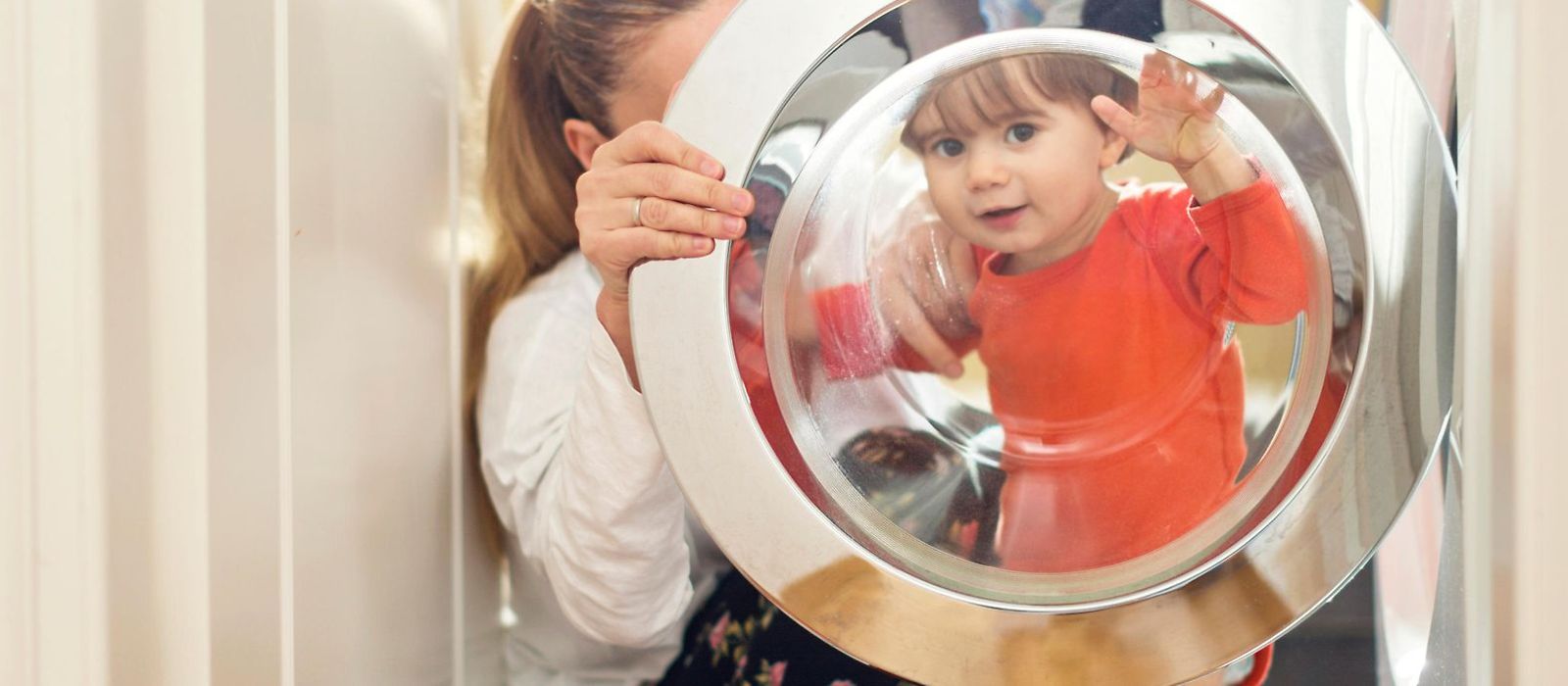 Frau mit Kind vor einer Waschmaschine
