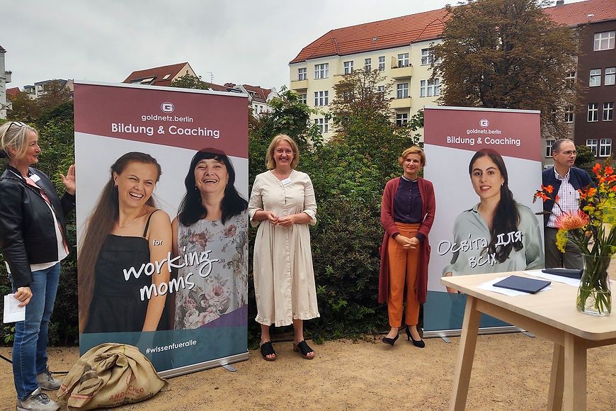 Bundesfamilienministerin Lisa Paus steht neben einem Goldnetzbanner, daneben steht eine weitere Frau