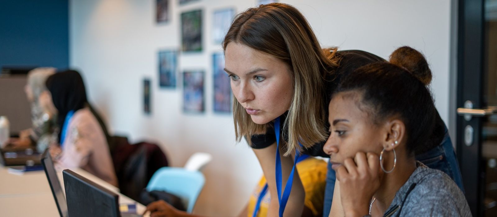 Unterrichtsraum: zwei Frauen im Vordergrund - schauen auf einen Laptop