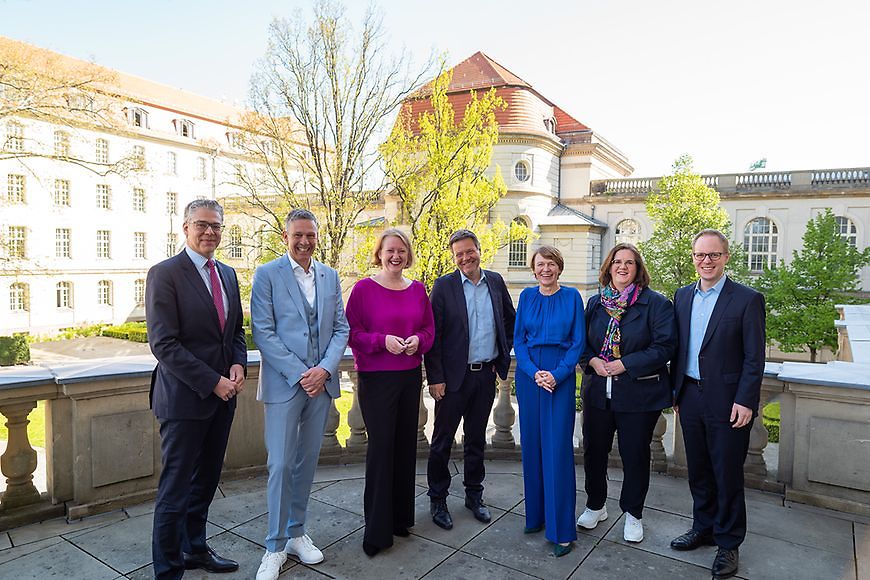 Lisa Paus steht draußen mit Teilnehmerinnen und Teilnehmern der vierten Fachtagung der "Initiative Klischeefrei"