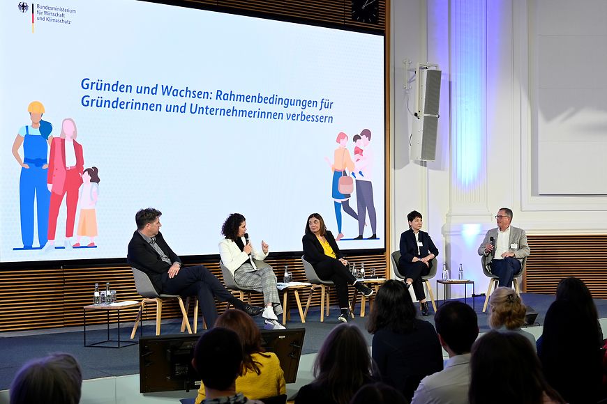 Bühne einer Podiumsdiskussion mit fünf Sprecherinnen und Sprechern