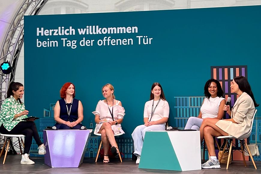 Sechs Frauen sitzen auf einem Podium und diskutieren