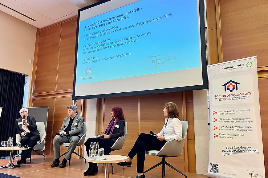 Ein Mann und drei Frauen sitzen auf einem Podium und diskutieren