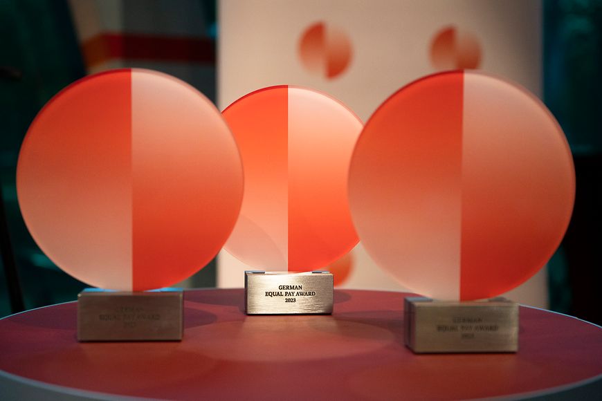 Drei Auszeichnungen des German Equal Pay Awards 2023 stehen auf einem Tisch.