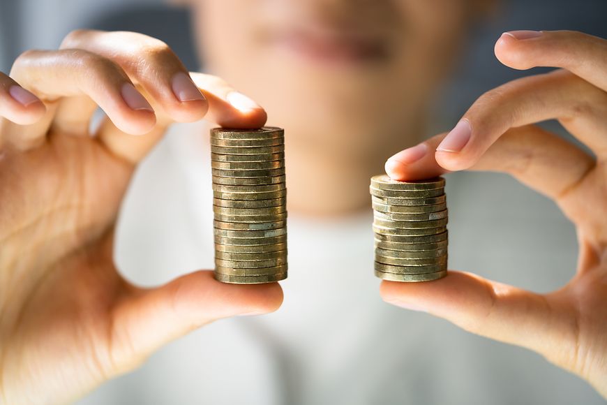 Zwei unterschiedliche hohe Münzstapel werden in zwei Händen gehalten