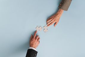 Top-Ansicht der Hände von Geschäftsfrau und Geschäftsmann, die zwei passende Puzzleteile verbindet 